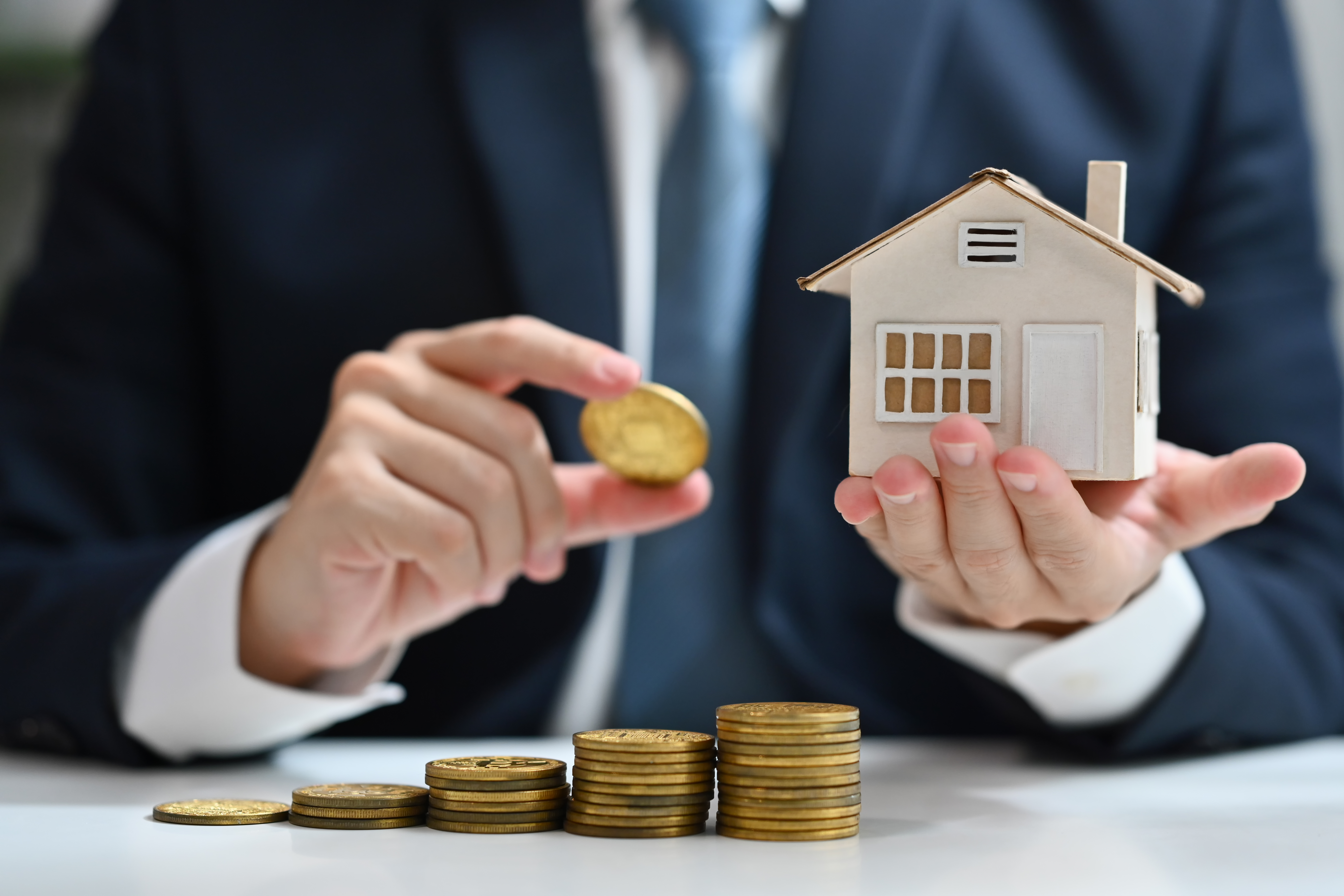 Businessman holding gold coin and house model. Real estate, property investment and save money concept